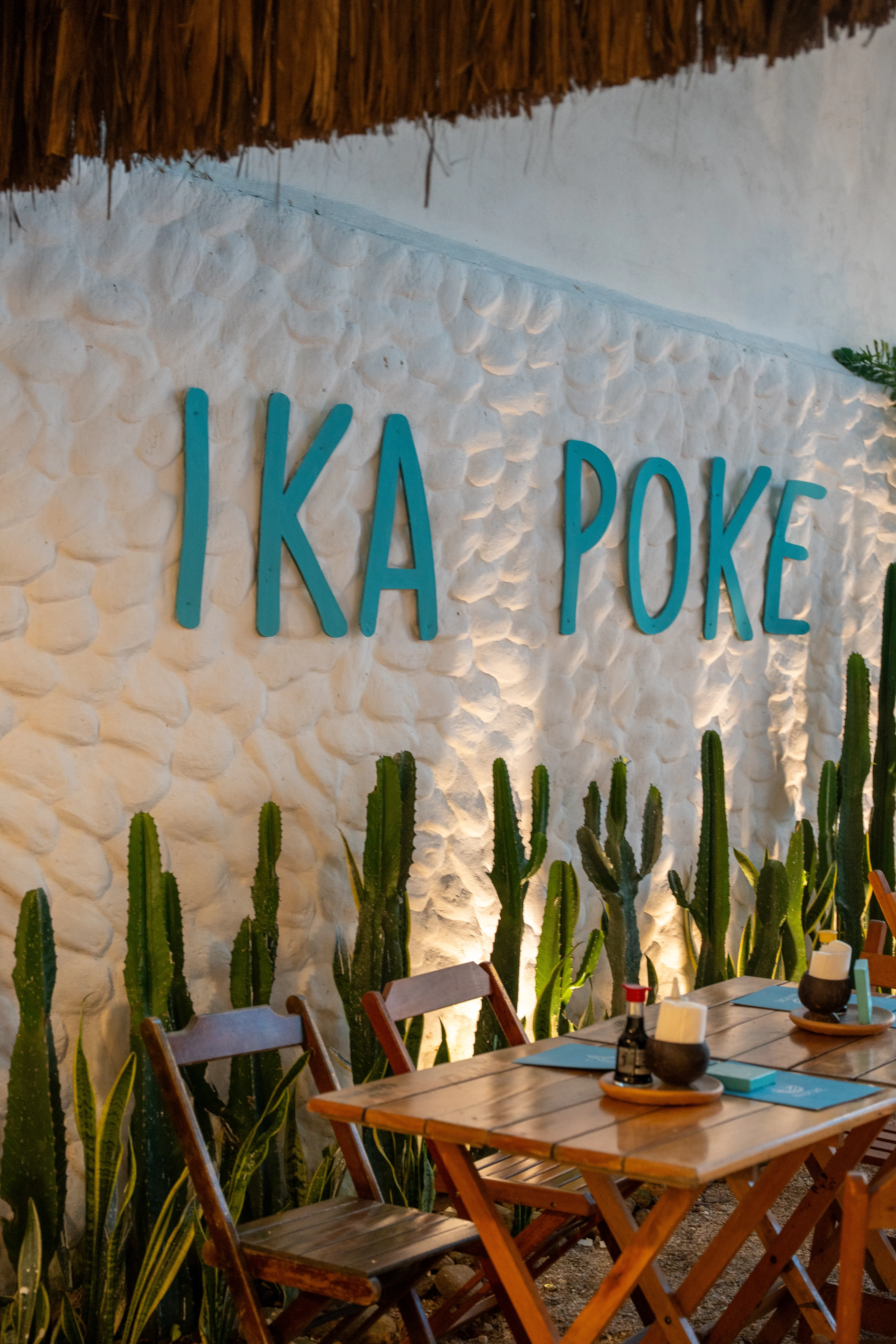 Parede do Ika Poke com o nome pintado e cactos em frente